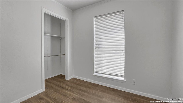 unfurnished bedroom featuring crown molding, dark wood-type flooring, and a closet