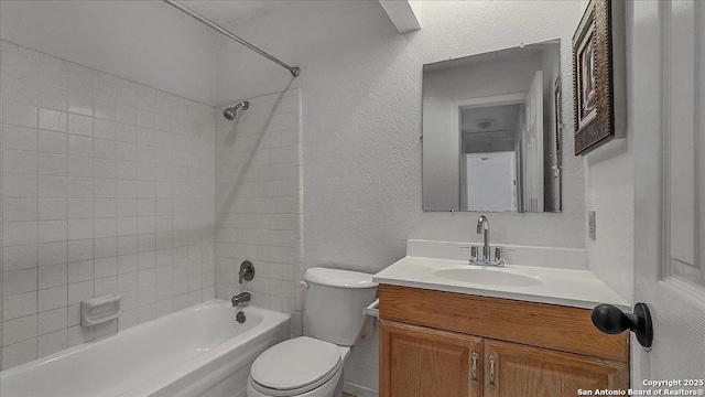 full bathroom featuring tiled shower / bath, vanity, and toilet