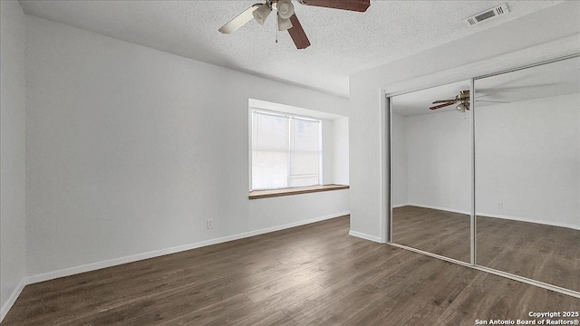 unfurnished bedroom with dark wood-type flooring, a closet, ceiling fan, and a textured ceiling