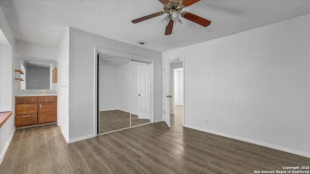 unfurnished bedroom featuring ceiling fan, dark hardwood / wood-style floors, a textured ceiling, and a closet