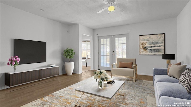 living room with french doors, ceiling fan, hardwood / wood-style floors, and a textured ceiling