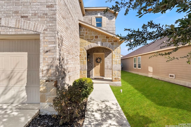 entrance to property with a garage and a lawn