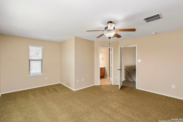 unfurnished bedroom with ceiling fan, ensuite bath, and light carpet