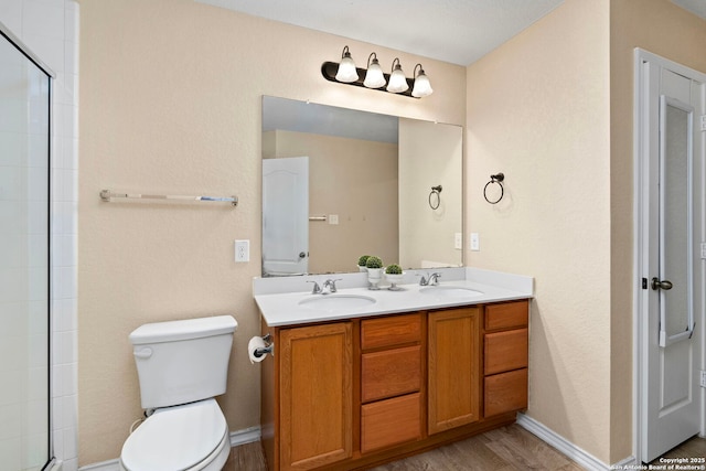 bathroom featuring vanity, wood-type flooring, a shower with shower door, and toilet