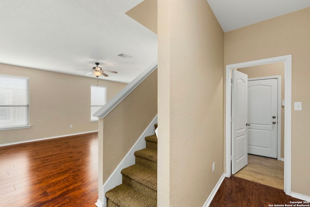 stairway with ceiling fan and wood-type flooring