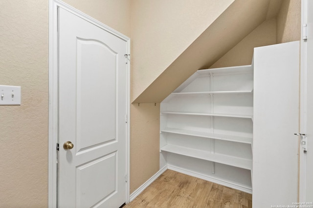 walk in closet with vaulted ceiling and light wood-type flooring