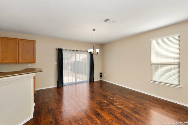 unfurnished dining area with dark hardwood / wood-style floors and a notable chandelier