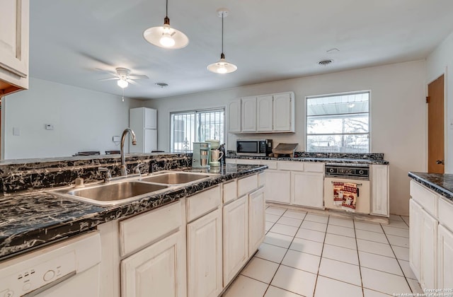 kitchen featuring sink, light tile patterned floors, dishwasher, white cabinetry, and hanging light fixtures