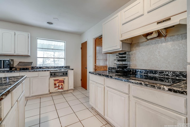 kitchen with light tile patterned flooring, white cabinetry, decorative backsplash, black cooktop, and white oven