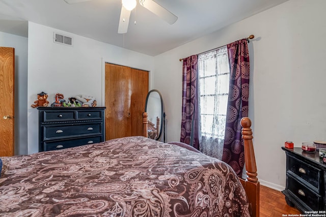 bedroom with parquet floors, ceiling fan, and a closet