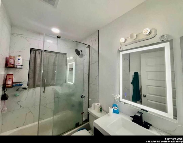 full bathroom featuring vanity, combined bath / shower with glass door, and toilet