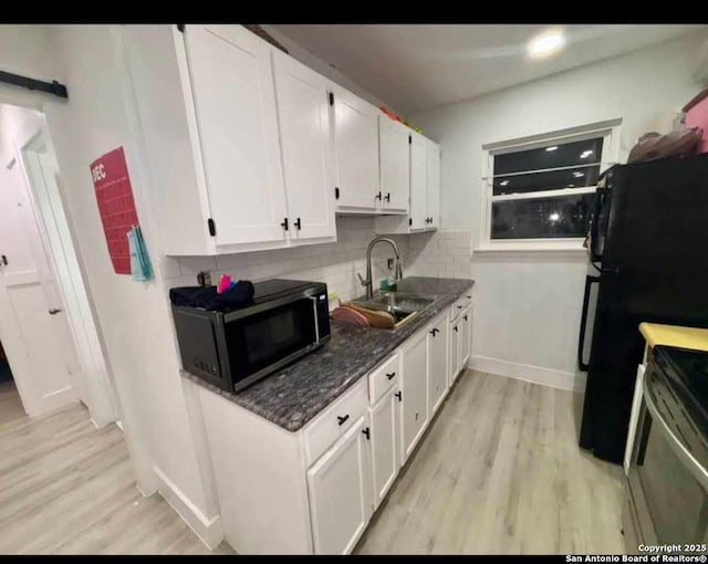 kitchen featuring light wood-type flooring, electric range, sink, and white cabinets