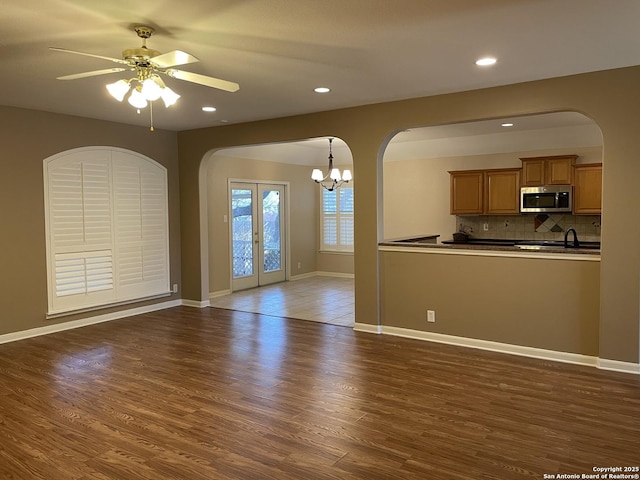 unfurnished living room featuring dark wood-type flooring and ceiling fan with notable chandelier