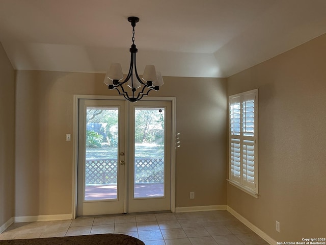 doorway to outside featuring a wealth of natural light, an inviting chandelier, and light tile patterned floors