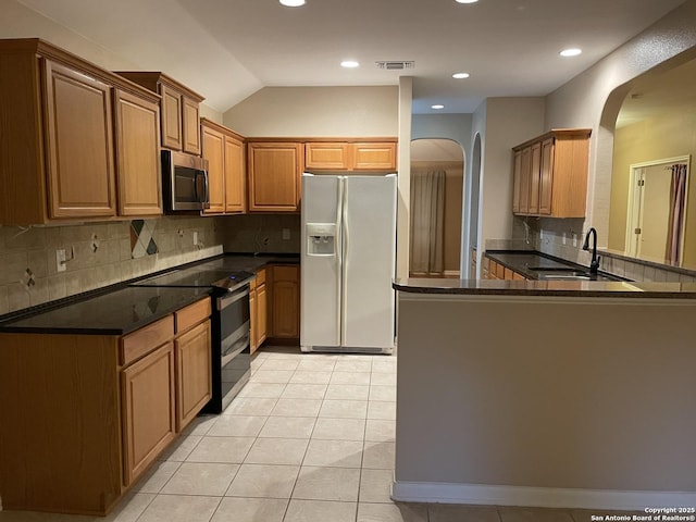 kitchen featuring light tile patterned flooring, sink, appliances with stainless steel finishes, kitchen peninsula, and decorative backsplash