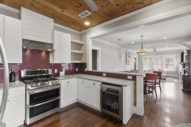 kitchen featuring decorative light fixtures, white cabinetry, beverage cooler, range with two ovens, and wall chimney range hood