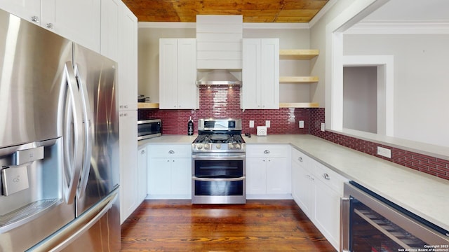 kitchen with wall chimney exhaust hood, appliances with stainless steel finishes, white cabinets, beverage cooler, and backsplash