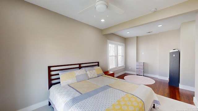 bedroom featuring ceiling fan, dark wood-type flooring, and beamed ceiling