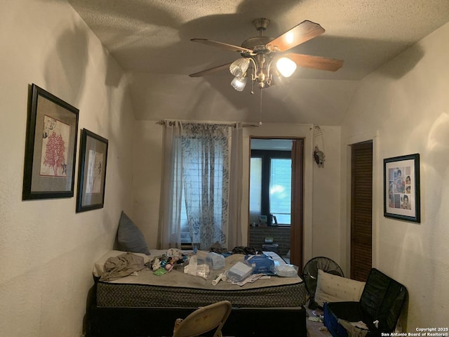 bedroom with ceiling fan, vaulted ceiling, and a textured ceiling