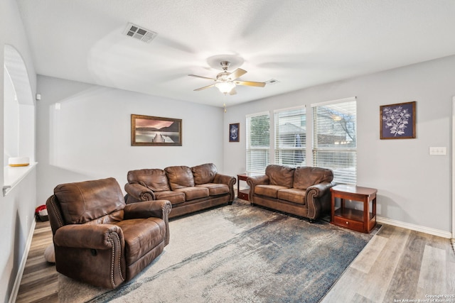 living room with a textured ceiling, wood-type flooring, and ceiling fan