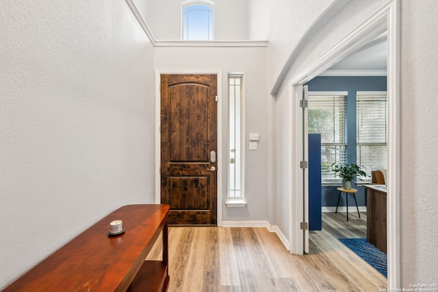 entrance foyer with crown molding and light hardwood / wood-style flooring