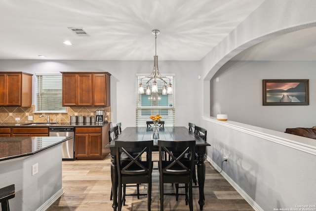 dining space featuring sink, a chandelier, and light hardwood / wood-style floors