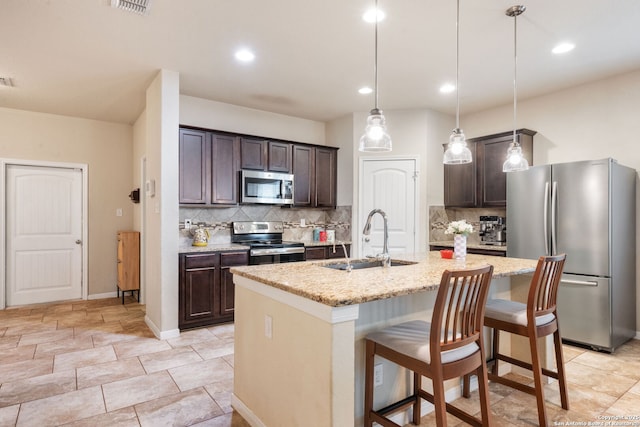 kitchen with stainless steel appliances, an island with sink, and dark brown cabinetry