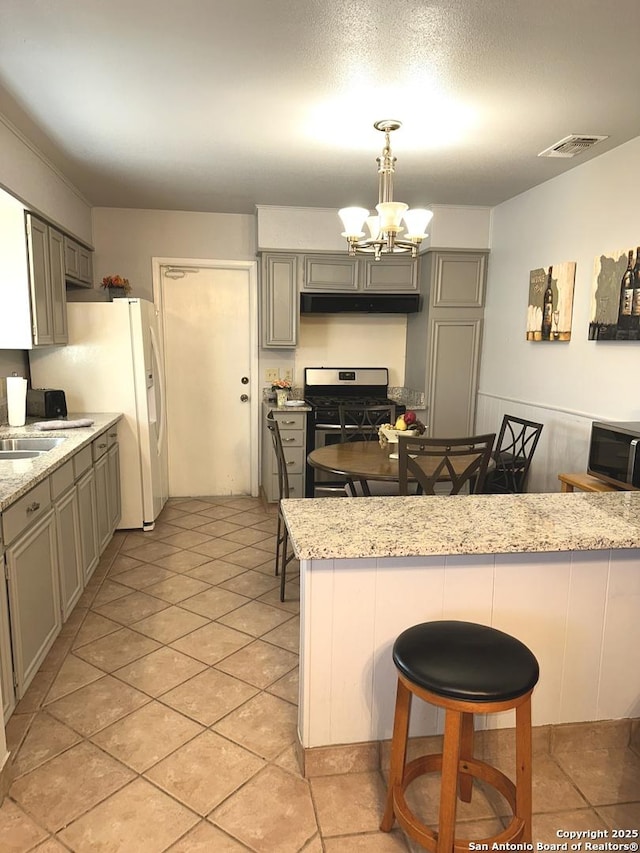 kitchen featuring appliances with stainless steel finishes, a kitchen bar, gray cabinets, and hanging light fixtures