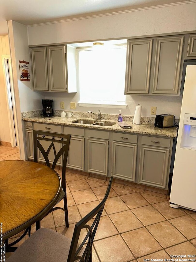 kitchen with gray cabinets, white refrigerator with ice dispenser, sink, and light tile patterned floors