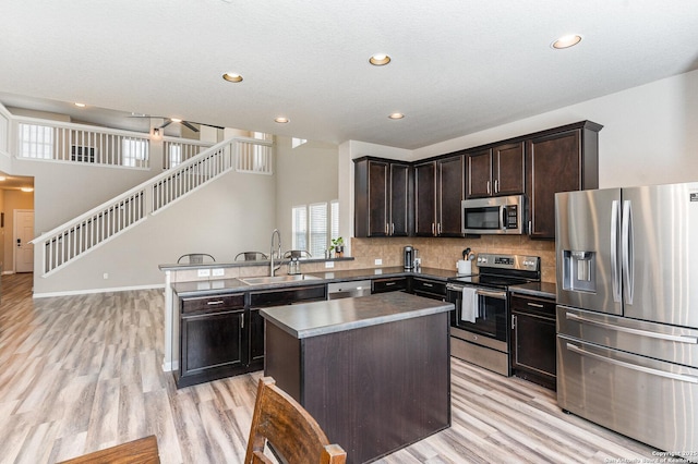 kitchen featuring sink, a center island, dark brown cabinets, appliances with stainless steel finishes, and backsplash