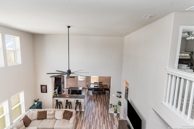 living room featuring hardwood / wood-style floors, a towering ceiling, and ceiling fan