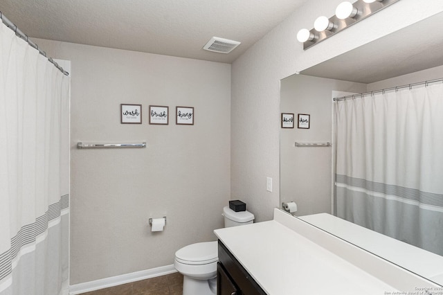 bathroom with tile patterned flooring, vanity, walk in shower, toilet, and a textured ceiling