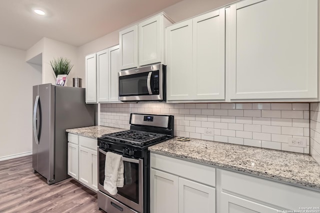 kitchen with stainless steel appliances, white cabinetry, and tasteful backsplash