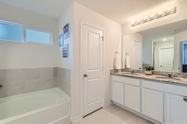 bathroom featuring tile patterned flooring, vanity, and a bath