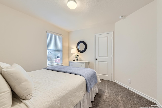 bedroom with dark colored carpet and a textured ceiling