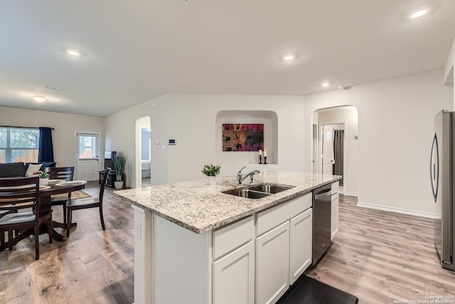 kitchen featuring sink, light hardwood / wood-style flooring, appliances with stainless steel finishes, white cabinets, and a center island with sink