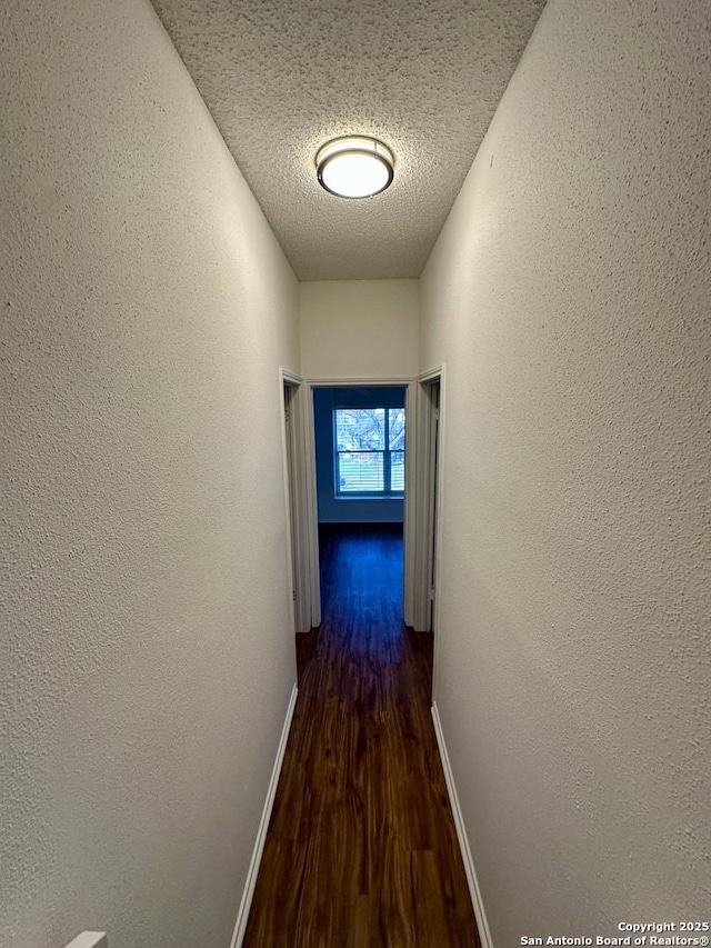 corridor featuring dark wood-type flooring and a textured ceiling