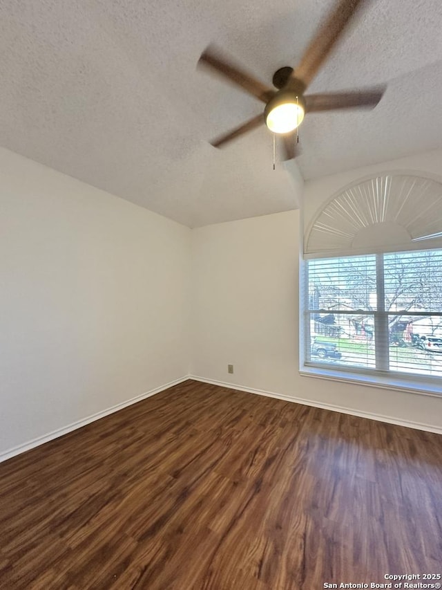 empty room with ceiling fan, lofted ceiling, dark wood-type flooring, and a textured ceiling