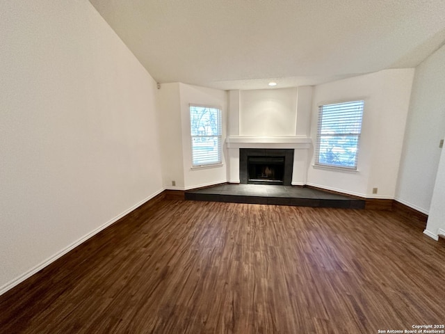 unfurnished living room with dark hardwood / wood-style flooring and a tiled fireplace