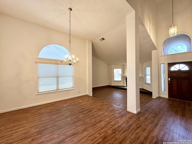 entryway with vaulted ceiling, an inviting chandelier, a textured ceiling, and dark hardwood / wood-style flooring