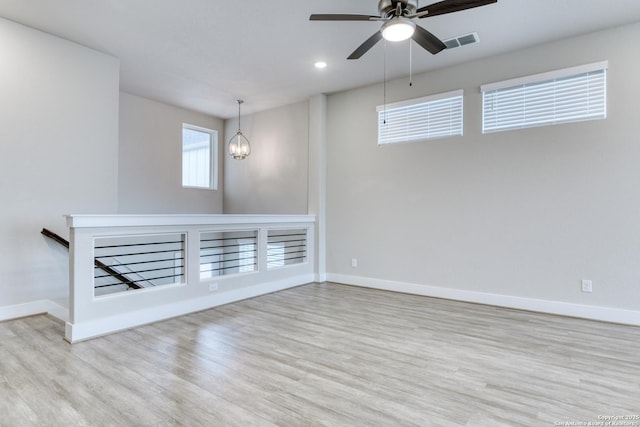 empty room featuring light hardwood / wood-style floors and ceiling fan with notable chandelier