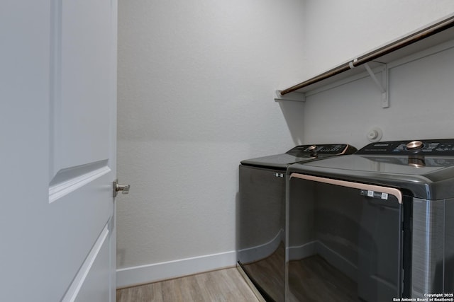 washroom with washing machine and dryer and light hardwood / wood-style flooring