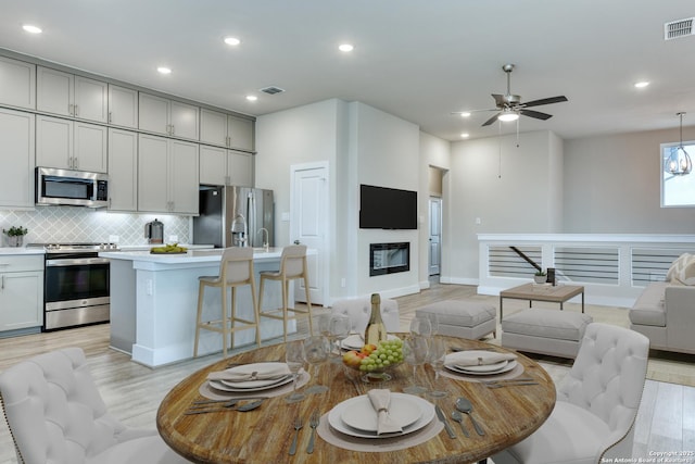 living room with ceiling fan and light hardwood / wood-style flooring