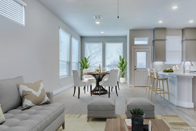 dining space with sink, a wealth of natural light, and light wood-type flooring