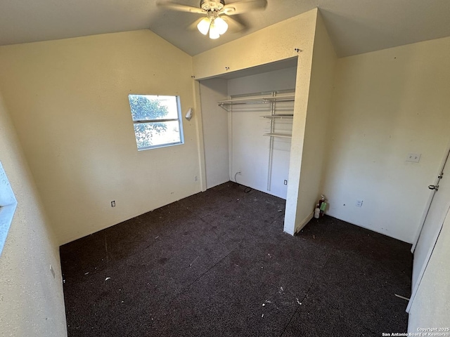 unfurnished bedroom with dark colored carpet, lofted ceiling, ceiling fan, and a closet