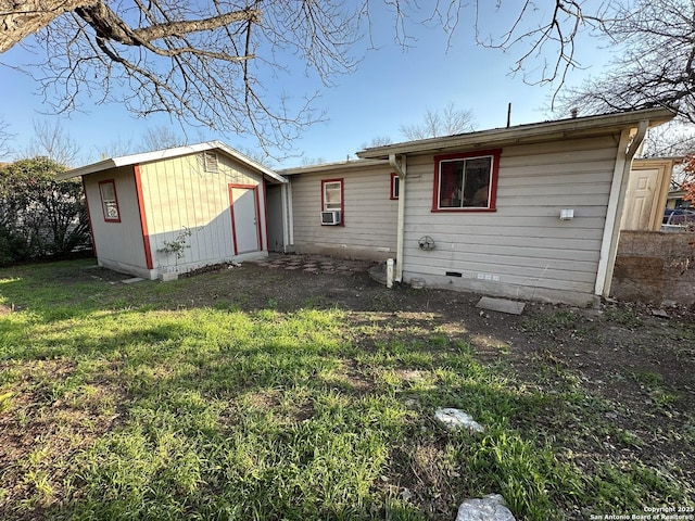 rear view of property featuring cooling unit, a storage unit, and a lawn