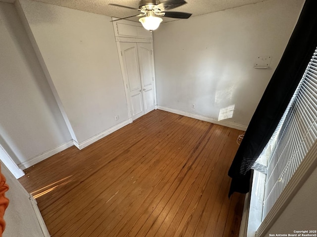 unfurnished bedroom with ceiling fan, wood-type flooring, a closet, and a textured ceiling