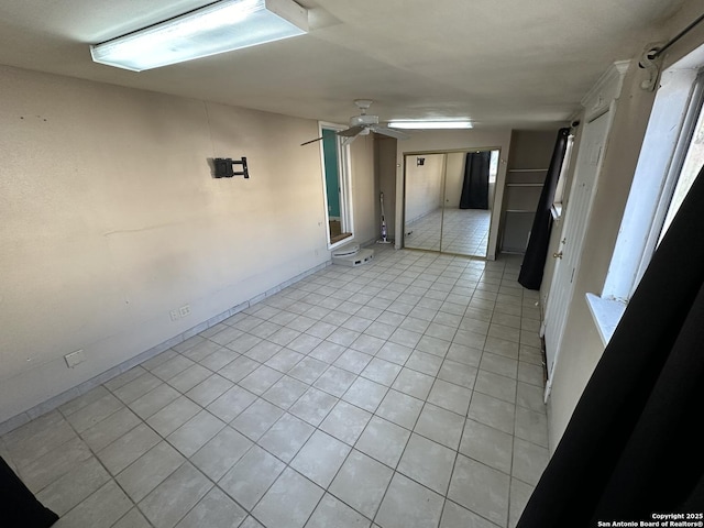 tiled empty room featuring ceiling fan