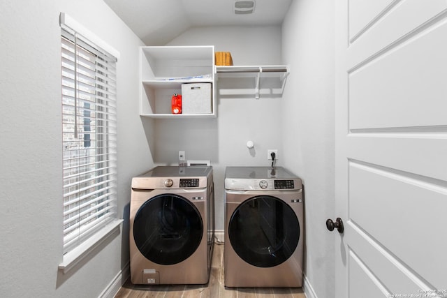 clothes washing area featuring a healthy amount of sunlight, washing machine and dryer, and light wood-type flooring