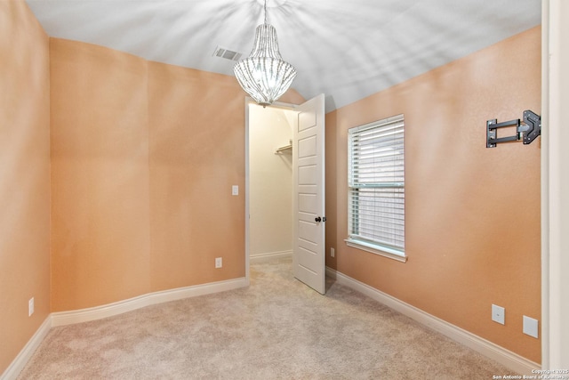 unfurnished bedroom featuring a spacious closet, light colored carpet, and an inviting chandelier